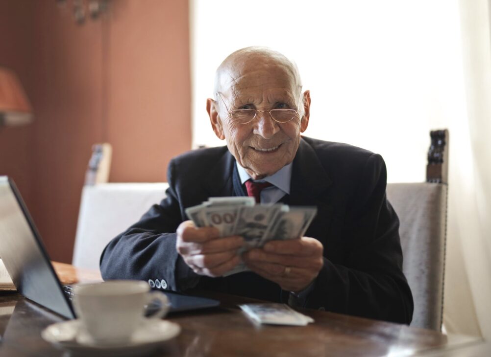old man holding cash to the camera